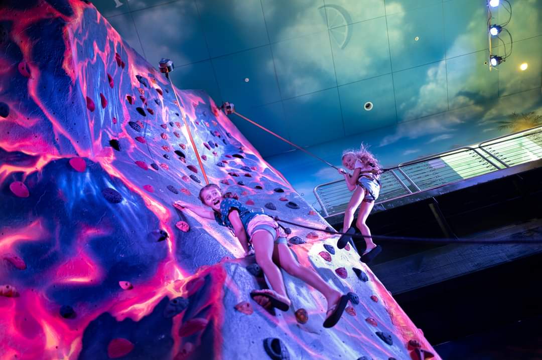 Two kids climbing on auto belays at the Margaritaville Biloxi Volcano Climbing Wall.