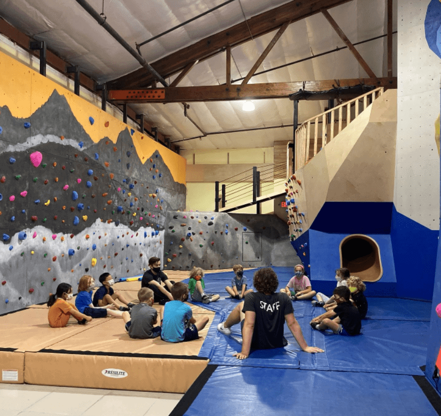Kids sitting in a circle at the Valley Rock Gym Kids Climbing Wall Area.