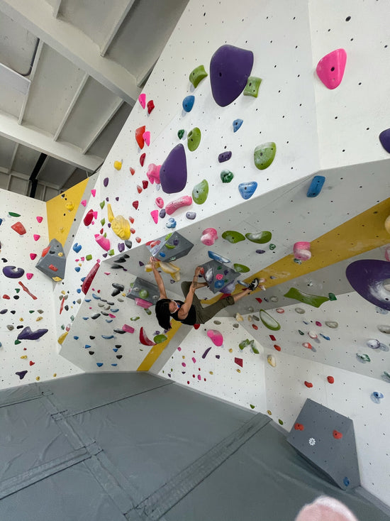 A woman climbing an overhung bouldering wall.