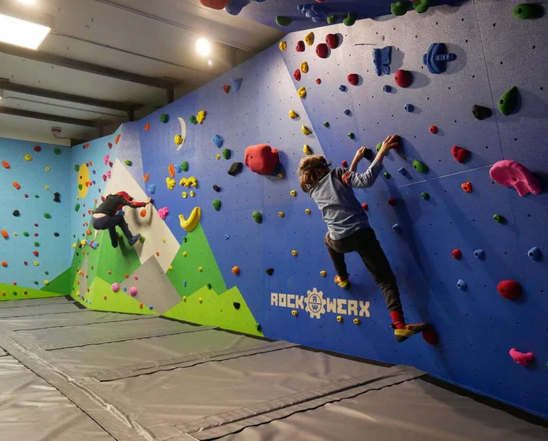 Kids climbing on a colorful scenic kids bouldering wall.
